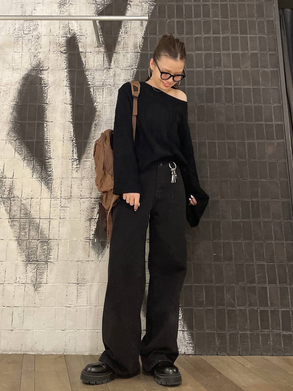 ブラック系のデニムパンツ、ブラック系のニット/セーター、ブラウン系のバックパック/リュックを着用したレディースの冬コーディネートの3枚目の写真