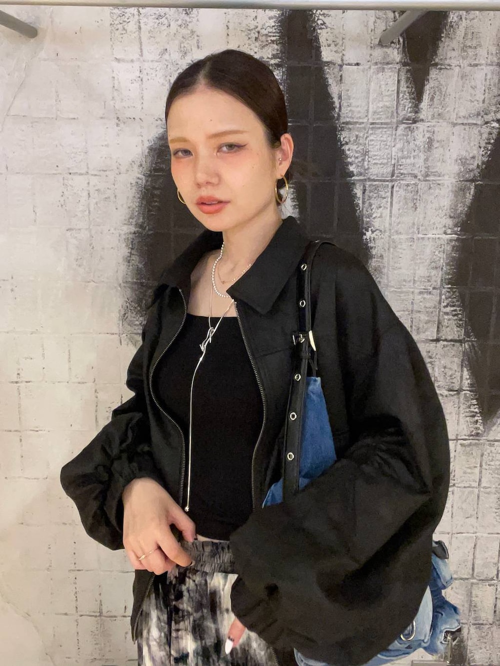 ブラック系のブルゾン、ブルー系のショルダーバッグ、ブラック系のブーツを着用したレディースの秋コーディネートの4枚目の写真