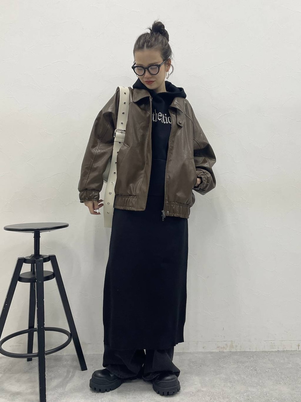 ホワイト系のショルダーバッグ、グレー系のデニムパンツ、ブラック系のブーツを着用したレディースの冬コーディネートの5枚目の写真