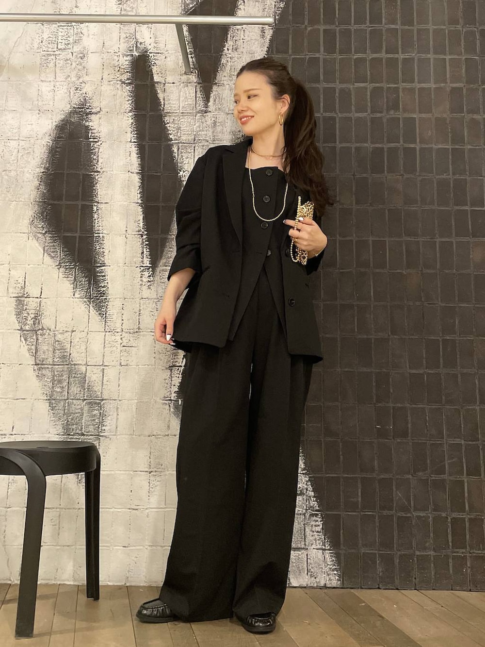 ブラック系のテーラードジャケット、ブラック系のローファー、ゴールド系のピアス（両耳用）を着用したレディースの冬コーディネートの6枚目の写真