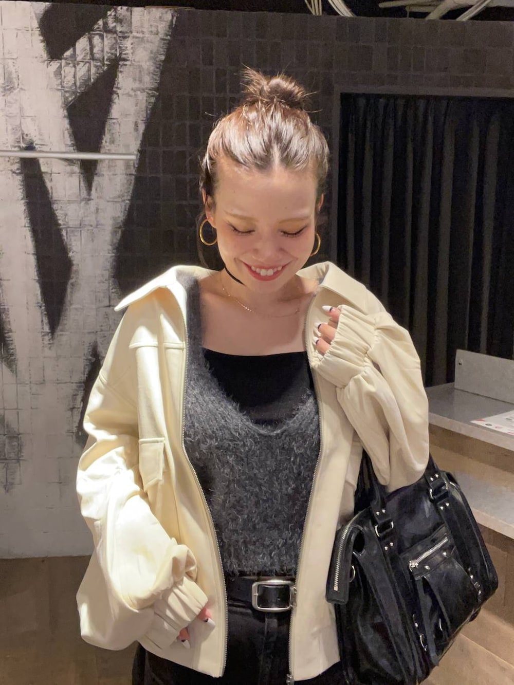 グレー系のデニムパンツ、ホワイト系のブルゾン、ブラック系のボストンバッグを着用したレディースの秋コーディネートの5枚目の写真