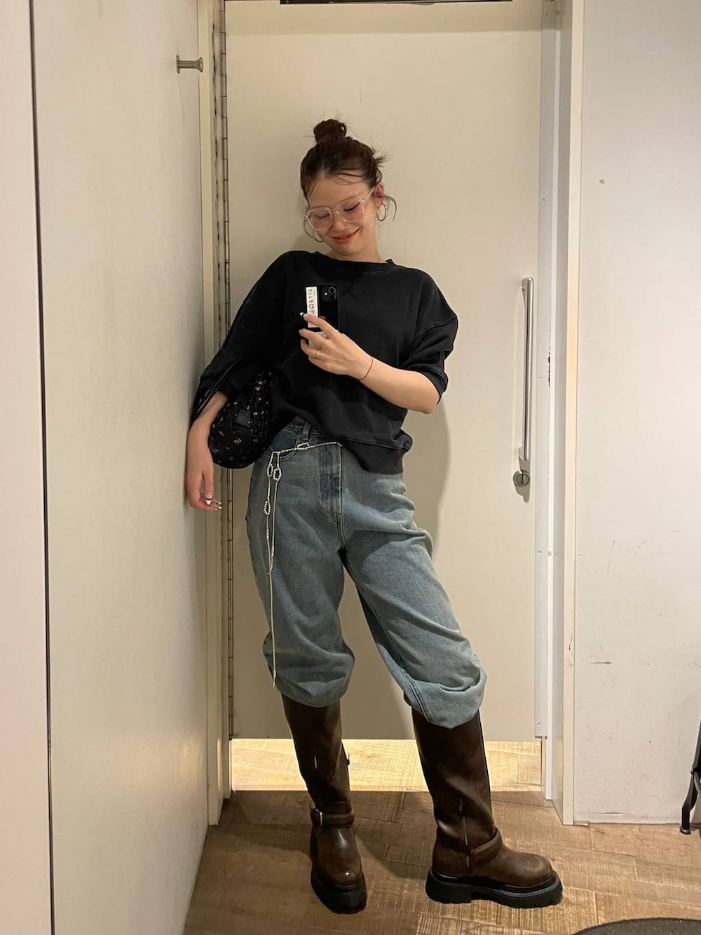 ブルー系のデニムパンツ、ブラック系のスウェット、ブラック系のショルダーバッグを着用したレディースの夏コーディネートの3枚目の写真