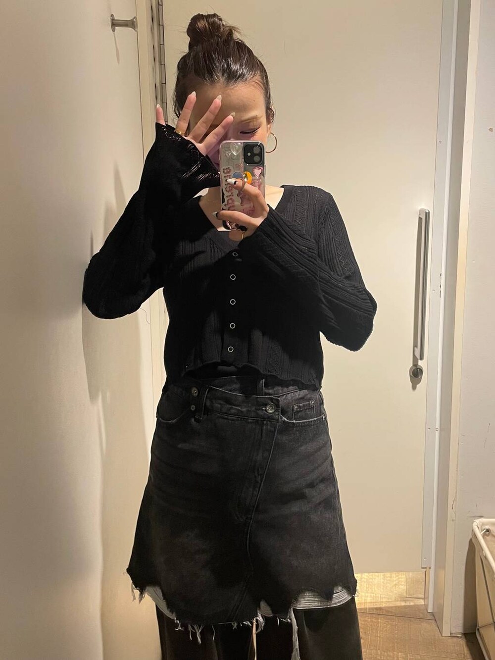 グレー系のデニムパンツ、ブラック系のカーディガン/ボレロ、ブラック系のデニムスカートを着用したレディースの秋コーディネートの6枚目の写真