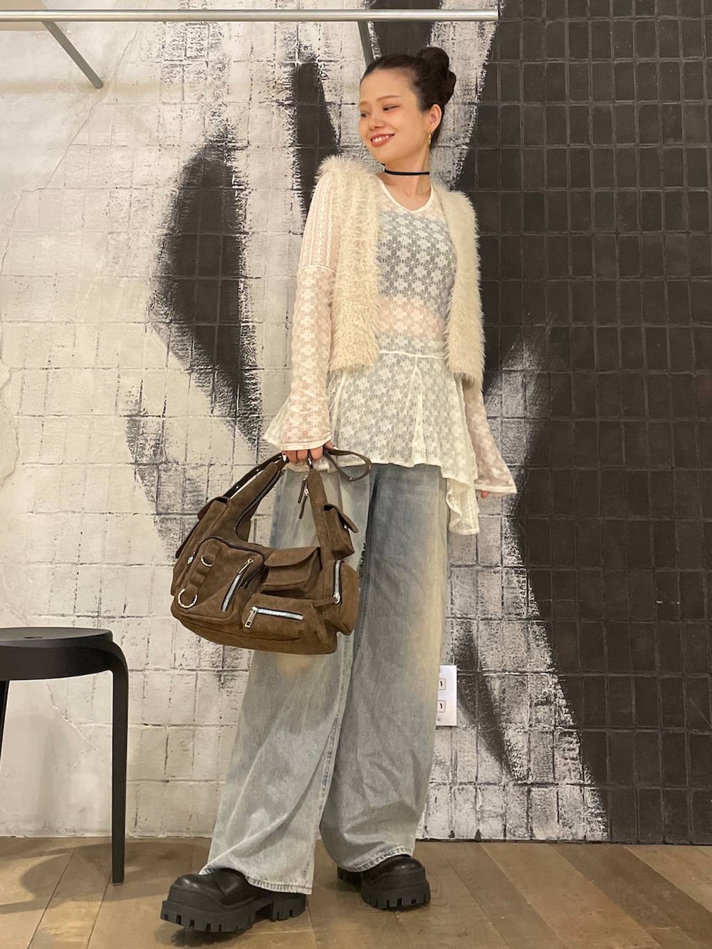 ホワイト系のベスト、ブルー系のデニムパンツ、ブラウン系のショルダーバッグを着用したレディースの秋コーディネートの4枚目の写真