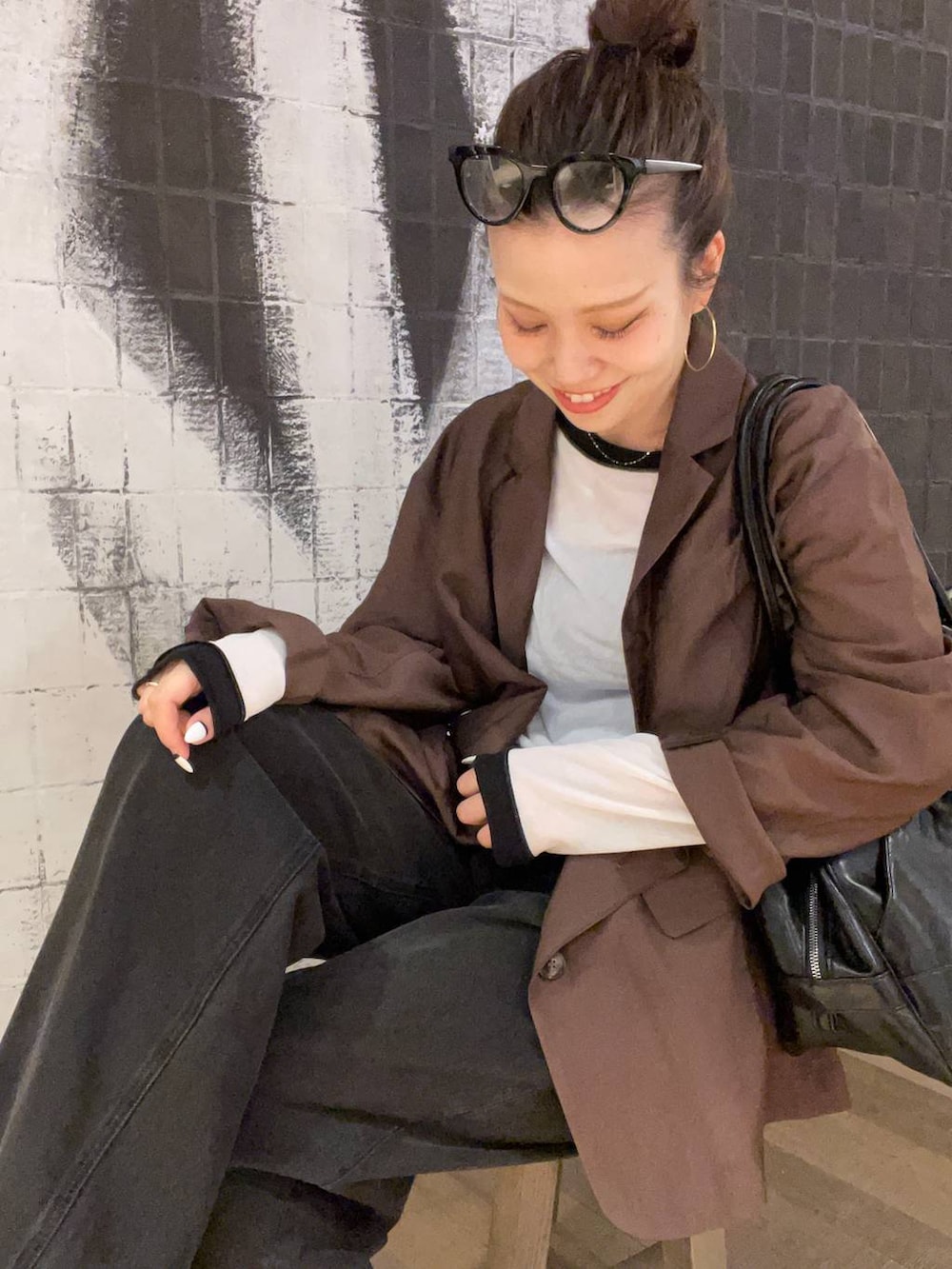 グレー系のデニムパンツ、ブラック系のボストンバッグ、ブラウン系のサンダルを着用したレディースの秋コーディネートの4枚目の写真