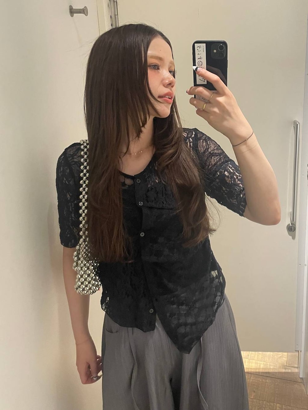 シルバー系のハンドバッグ、グレー系のスラックス、ブラック系のバレエシューズを着用したレディースの夏コーディネートの3枚目の写真