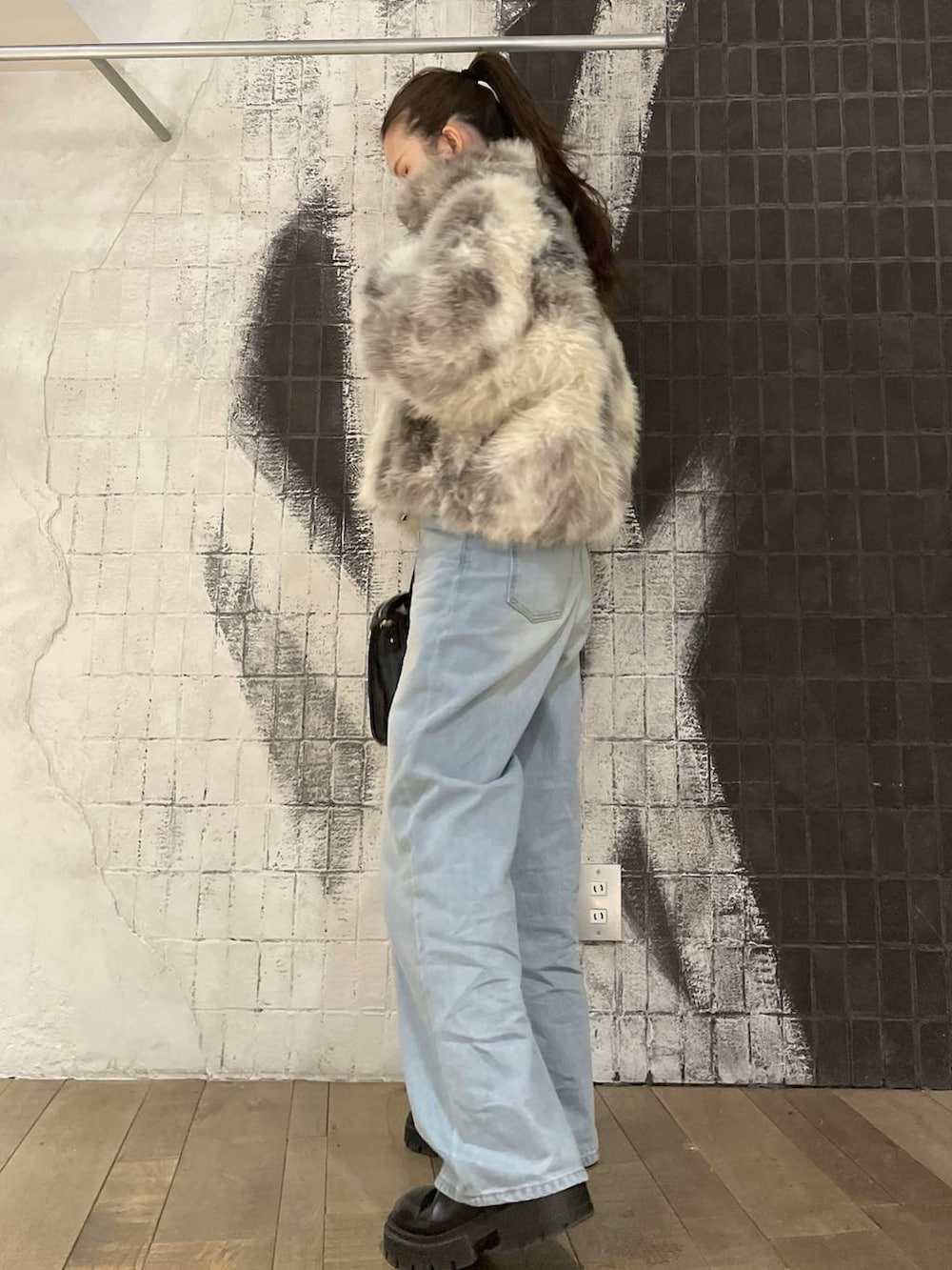 グレー系のブルゾン、ブラック系のボストンバッグ、ブルー系のニット/セーターを着用したレディースの冬コーディネートの3枚目の写真