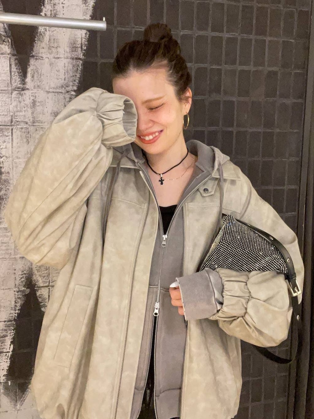 ベージュ系のブルゾン、グレー系のパーカー、ブラック系のブーツを着用したレディースの冬コーディネートの6枚目の写真