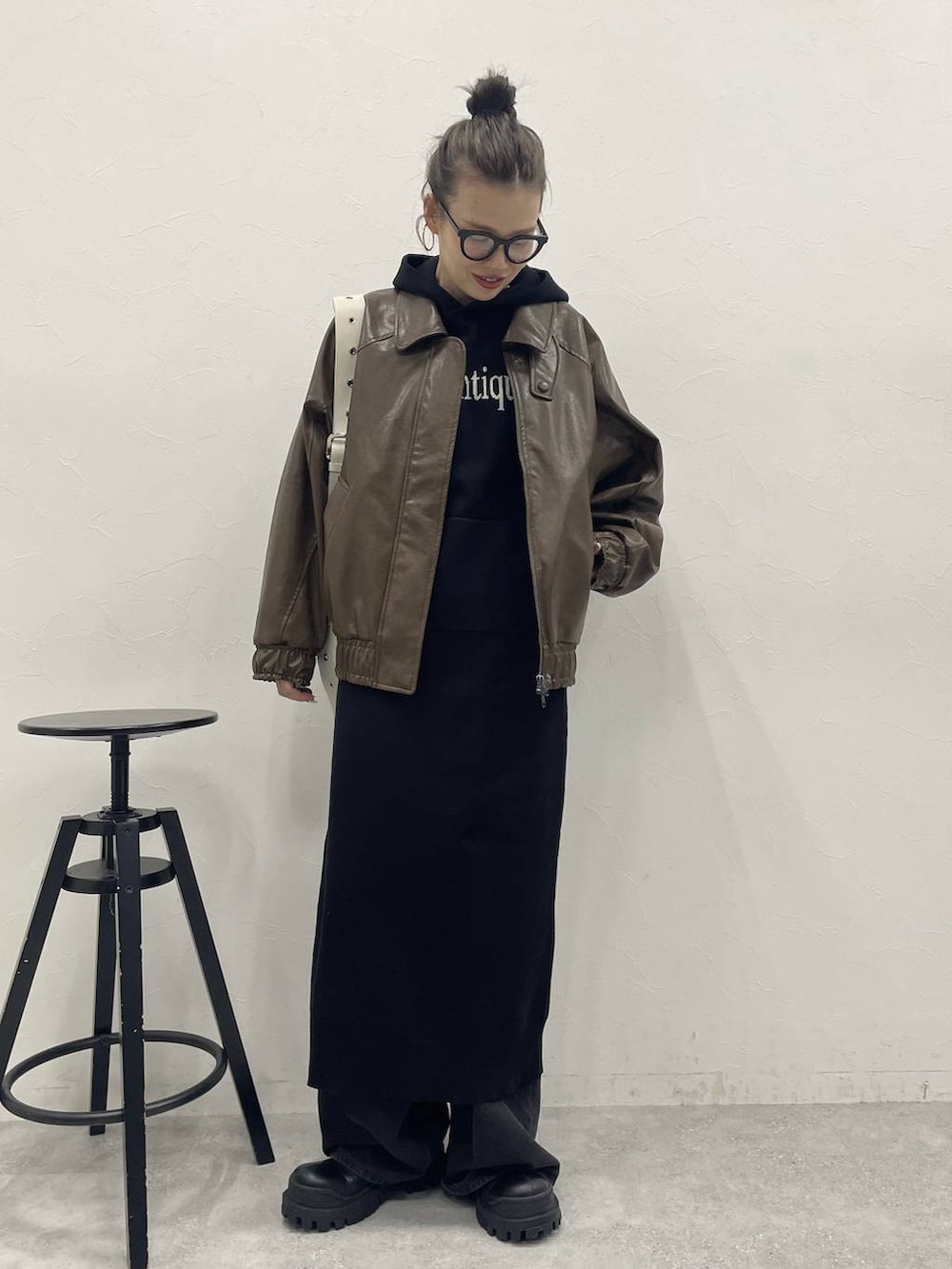 ホワイト系のショルダーバッグ、グレー系のデニムパンツ、ブラック系のブーツを着用したレディースの冬コーディネートの4枚目の写真