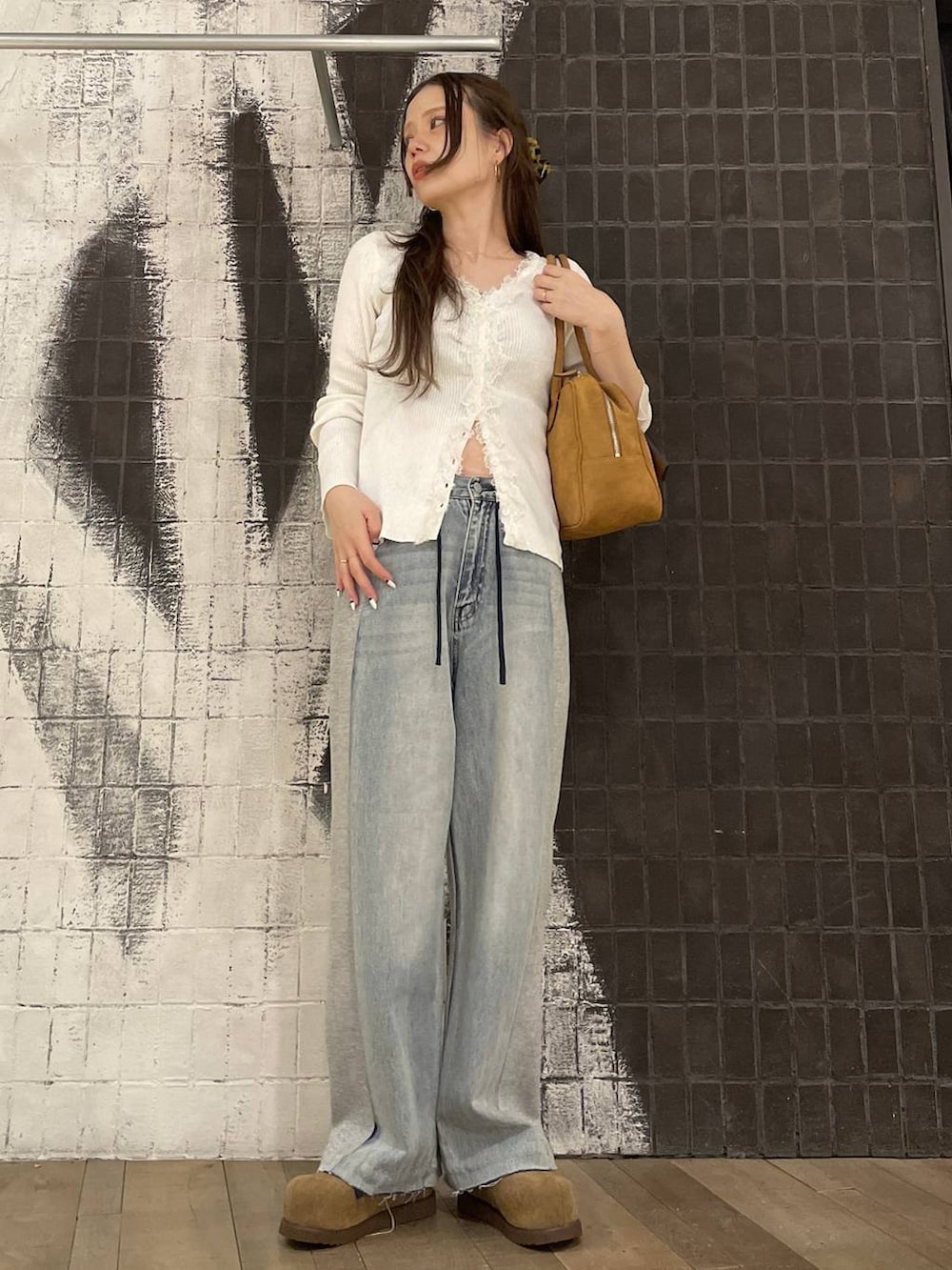 ブラウン系のボストンバッグ、ベージュ系のモカシン/デッキシューズ、ブルー系のデニムパンツを着用したレディースの春コーディネートの6枚目の写真