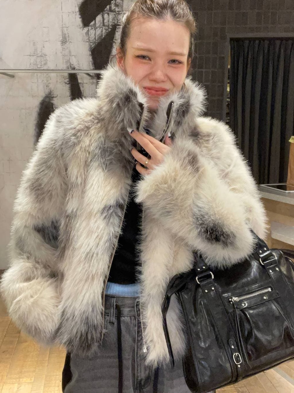 グレー系のブルゾン、ブラック系のボストンバッグ、ブラック系のデニムパンツを着用したレディースの冬コーディネートの5枚目の写真