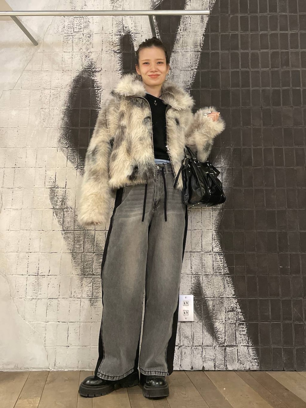 グレー系のブルゾン、ブラック系のボストンバッグ、ブラック系のデニムパンツを着用したレディースの冬コーディネートの2枚目の写真