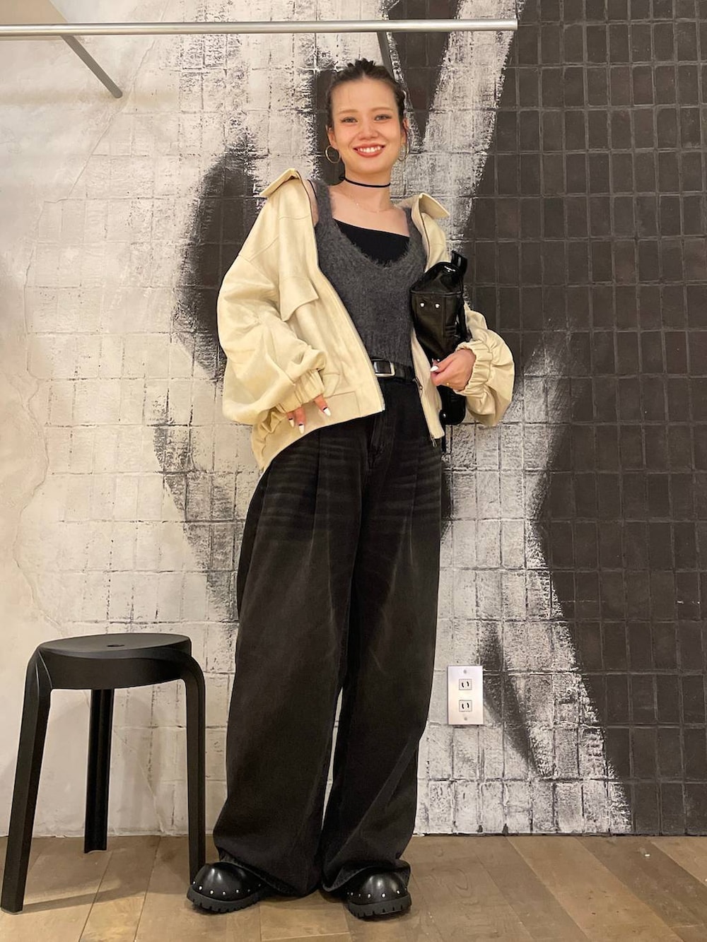 グレー系のデニムパンツ、ホワイト系のブルゾン、ブラック系のボストンバッグを着用したレディースの秋コーディネートの4枚目の写真