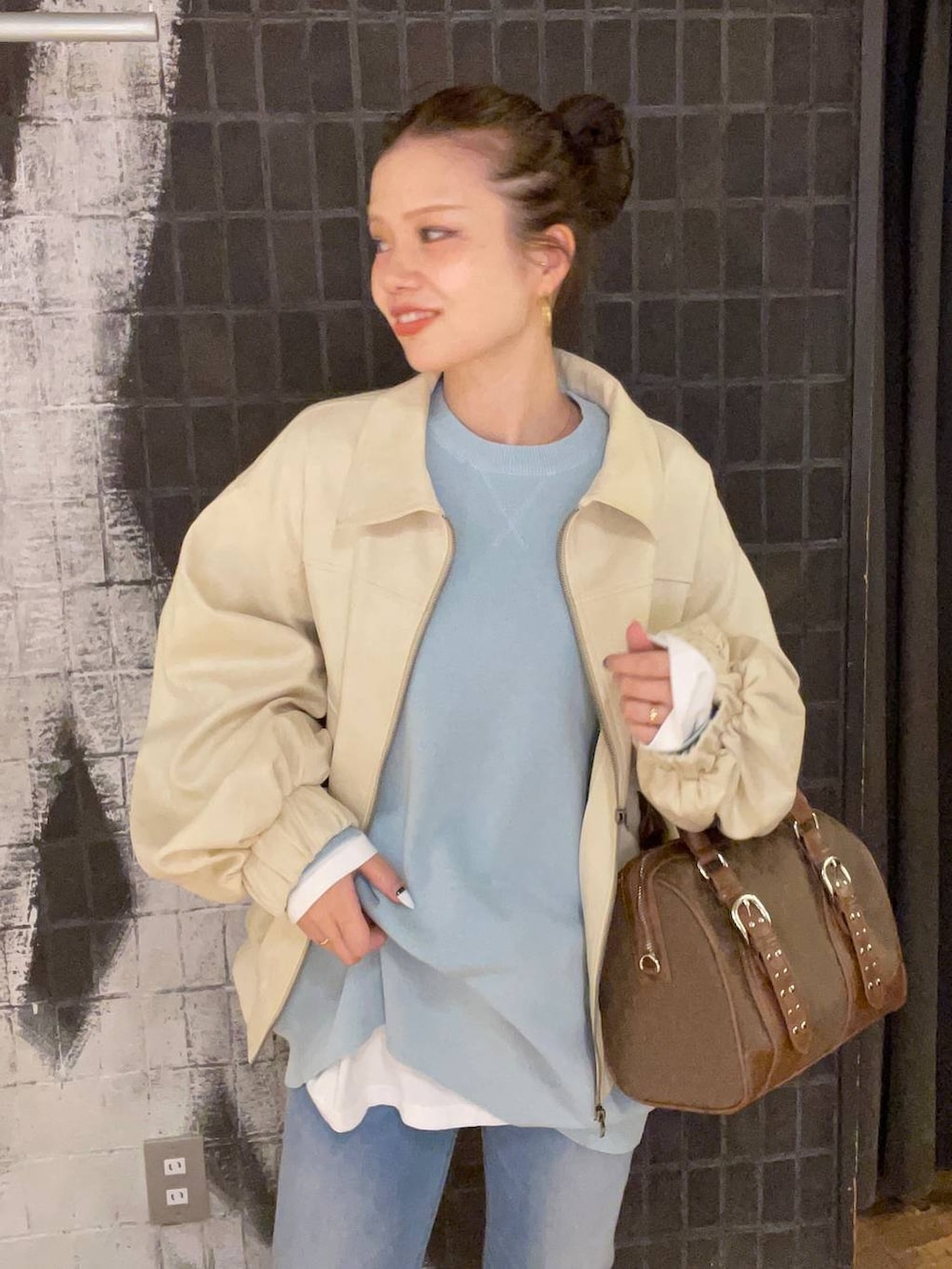 ブルー系のニット/セーター、ホワイト系のブルゾン、グリーン系のボストンバッグを着用したレディースの秋コーディネートの6枚目の写真