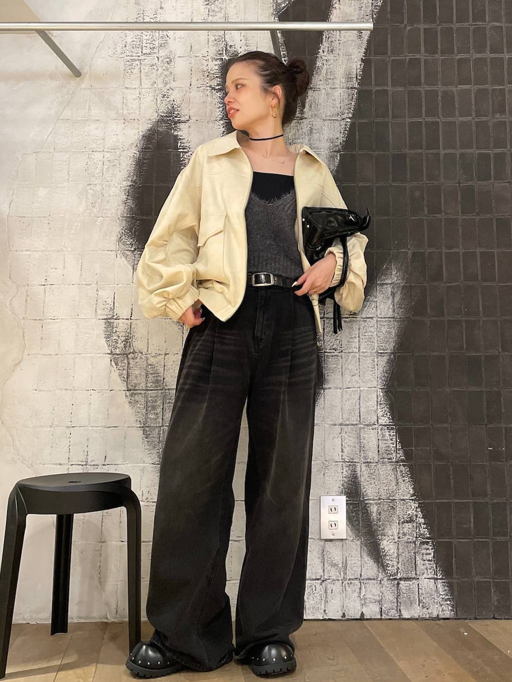 グレー系のデニムパンツ、ホワイト系のブルゾン、ブラック系のボストンバッグを着用したレディースの秋コーディネートの2枚目の写真