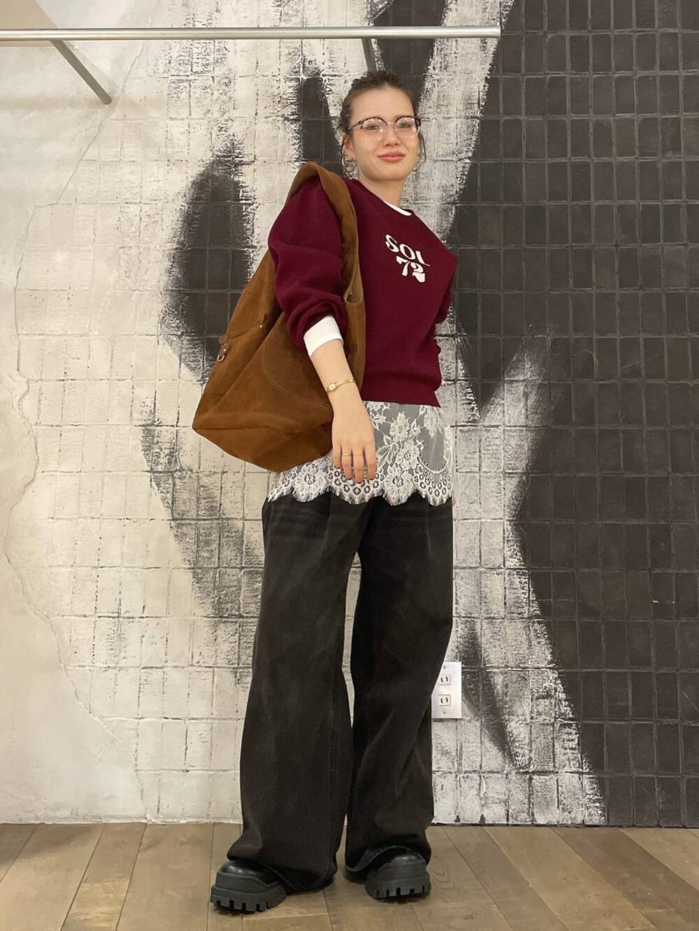 グレー系のデニムパンツ、ブラック系のブーツ、ブラウン系のトートバッグを着用したレディースの秋コーディネートの3枚目の写真