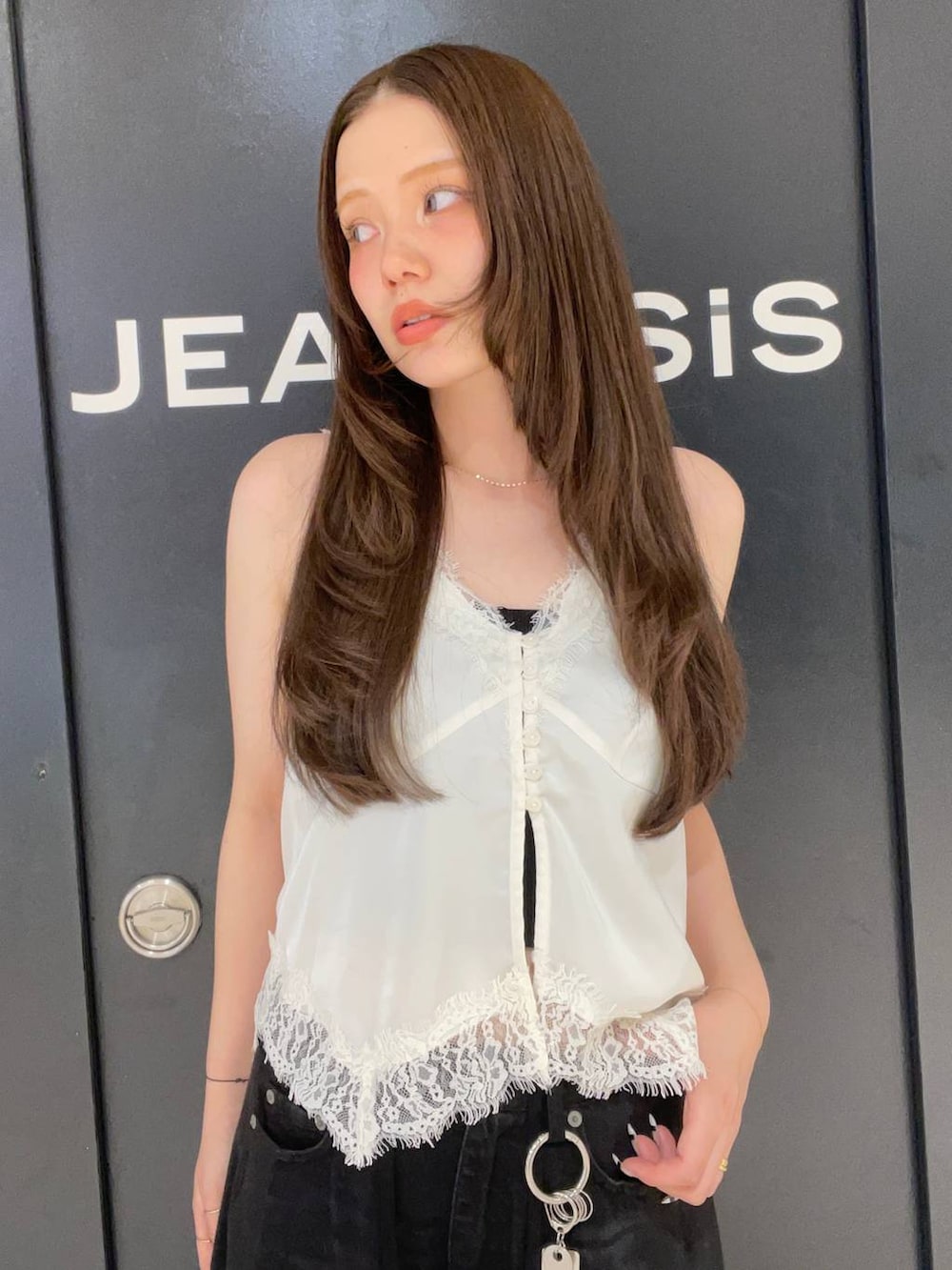 ブラック系のデニムパンツ、ホワイト系のベスト、ブラック系のベルトを着用したレディースの夏コーディネートの5枚目の写真