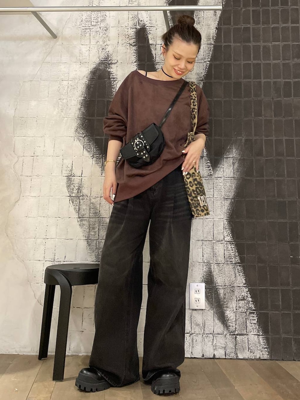 グレー系のデニムパンツ、ブラック系のショルダーバッグ、ブラック系のブーツを着用したレディースの秋コーディネートの6枚目の写真