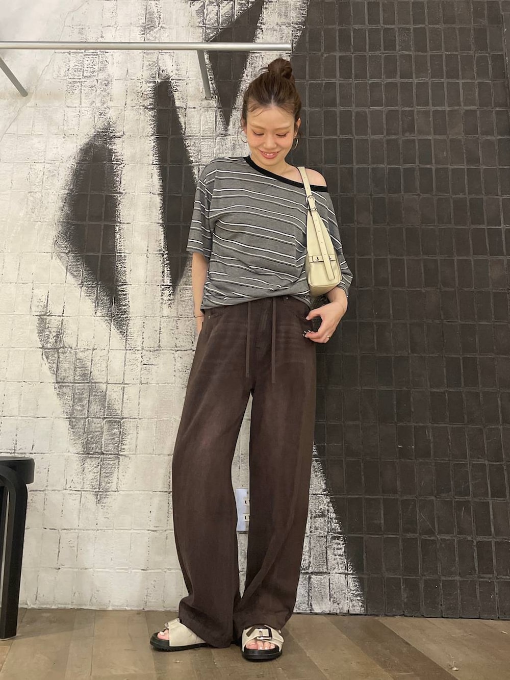 グレー系のTシャツ/カットソー、ブラウン系のデニムパンツ、ホワイト系のサンダルを着用したレディースの夏コーディネートの3枚目の写真