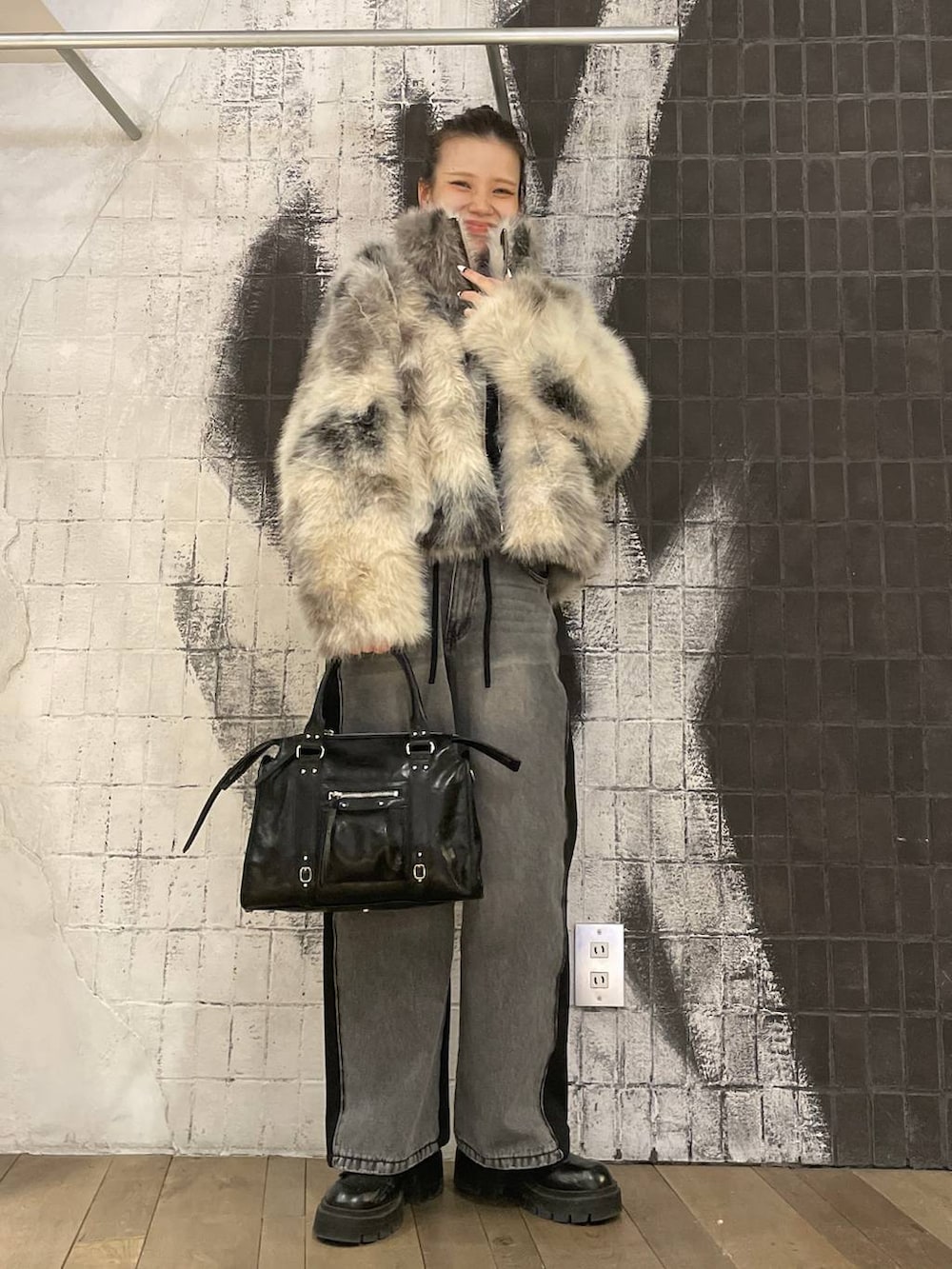 グレー系のブルゾン、ブラック系のボストンバッグ、ブラック系のデニムパンツを着用したレディースの冬コーディネートの6枚目の写真