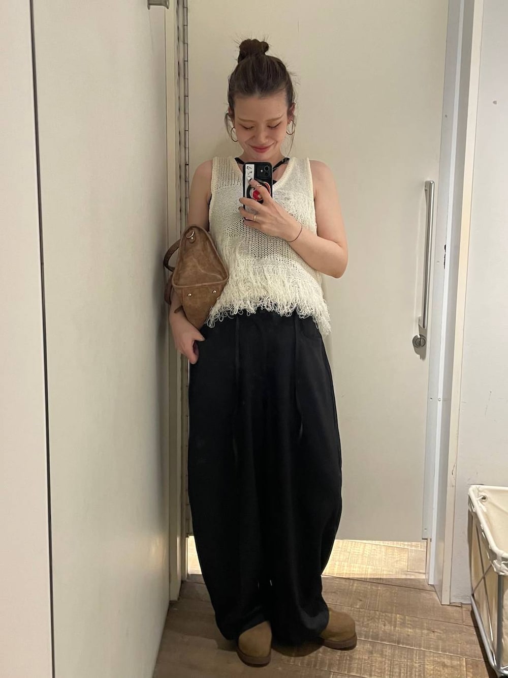 ベージュ系のモカシン/デッキシューズ、ブラウン系のボストンバッグ、ホワイト系のベストを着用したレディースの春コーディネートの2枚目の写真