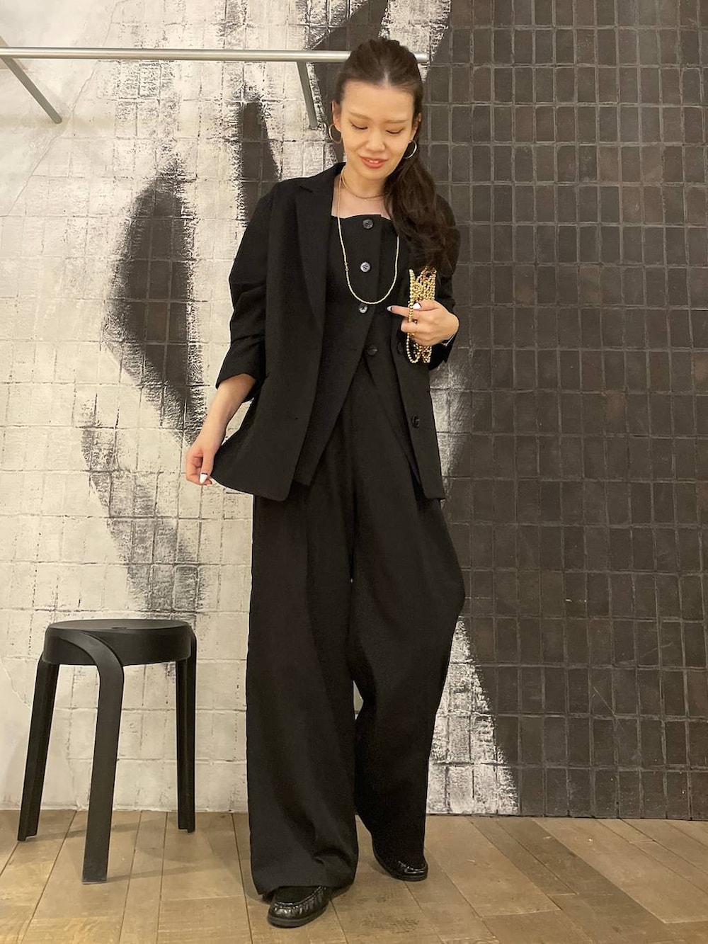 ブラック系のテーラードジャケット、ブラック系のローファー、ゴールド系のピアス（両耳用）を着用したレディースの冬コーディネートの2枚目の写真