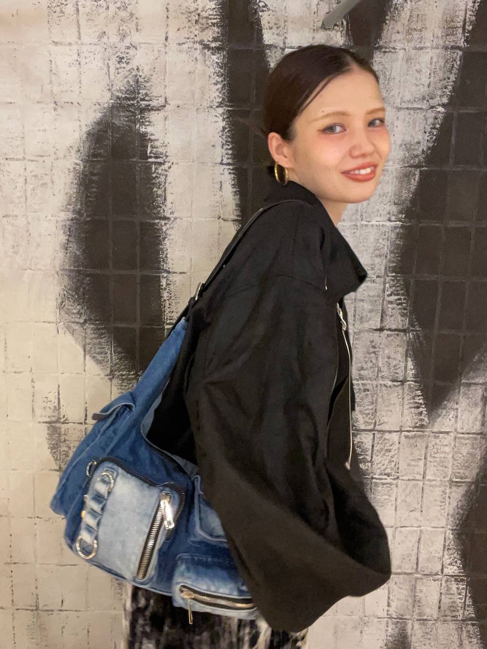 ブラック系のブルゾン、ブルー系のショルダーバッグ、ブラック系のブーツを着用したレディースの秋コーディネートの6枚目の写真