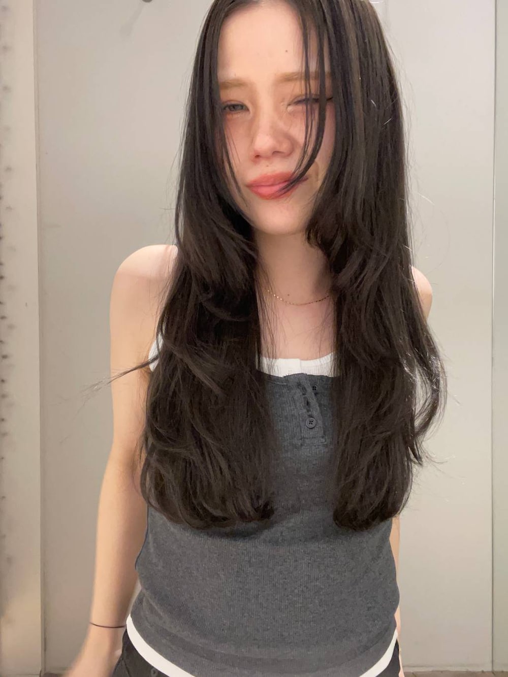 ブラック系のデニムパンツ、ホワイト系のタンクトップ、グレー系のタンクトップを着用したレディースの春コーディネートの3枚目の写真