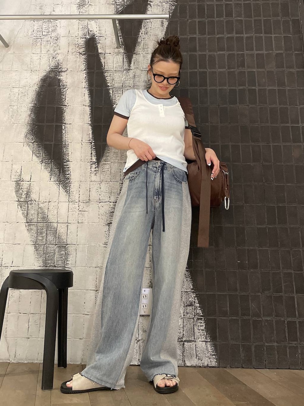 ブラウン系のショルダーバッグ、ブルー系のデニムパンツ、ホワイト系のタンクトップを着用したレディースの春コーディネートの2枚目の写真