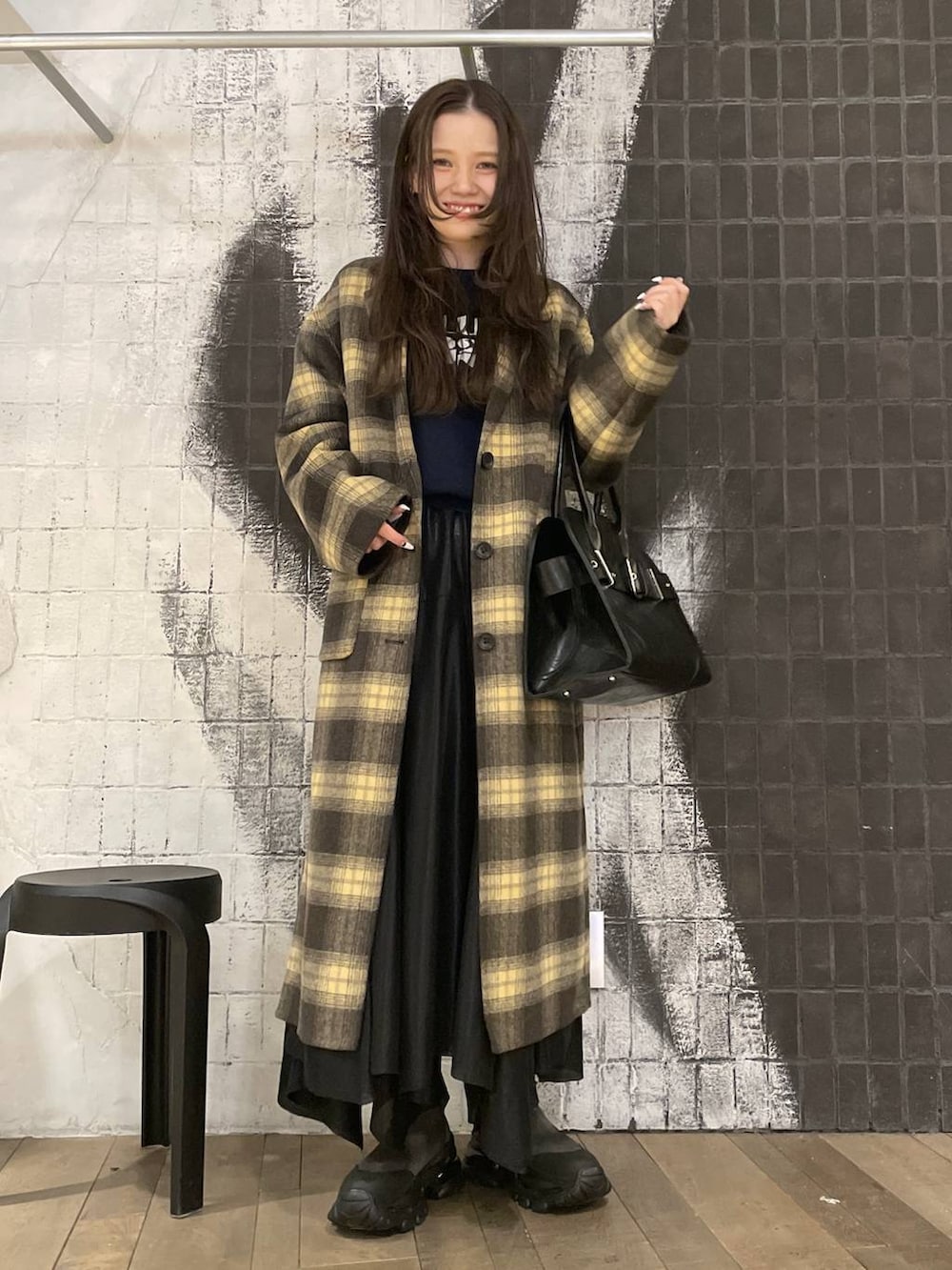 グレー系のブーツ、ブラウン系のチェスターコート、ブラック系のショルダーバッグを着用したレディースの冬コーディネートの3枚目の写真