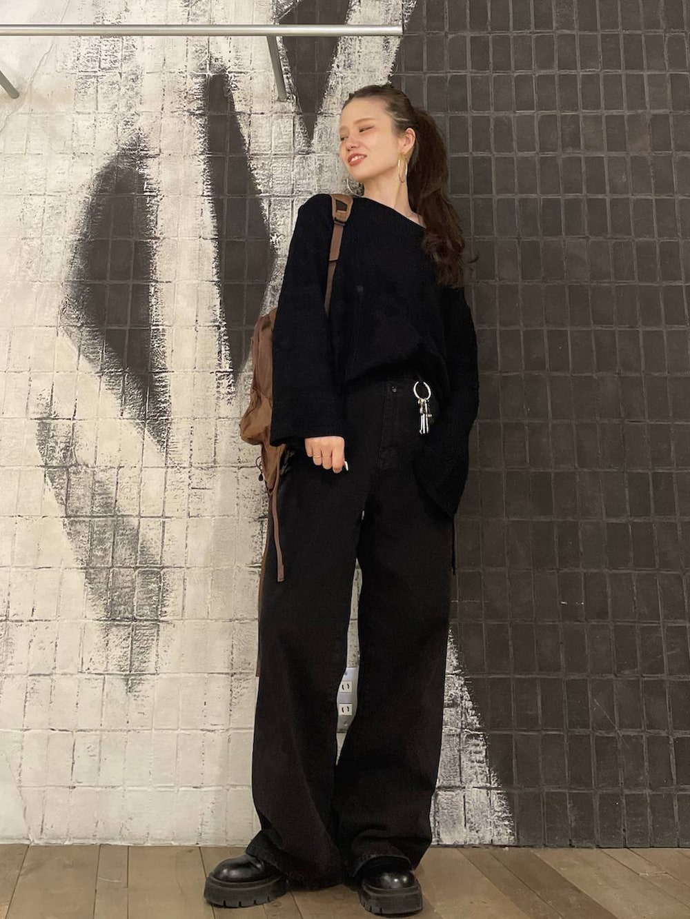 ブラック系のデニムパンツ、ブラック系のニット/セーター、ブラウン系のバックパック/リュックを着用したレディースの冬コーディネートの5枚目の写真