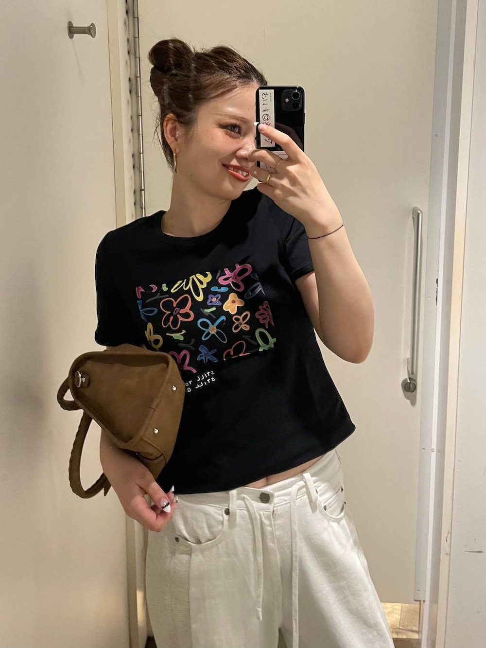ブラック系のTシャツ/カットソー、ホワイト系のデニムパンツ、ブラウン系のボストンバッグを着用したレディースの夏コーディネートの4枚目の写真