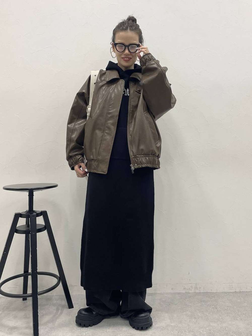 ホワイト系のショルダーバッグ、グレー系のデニムパンツ、ブラック系のブーツを着用したレディースの冬コーディネートの2枚目の写真