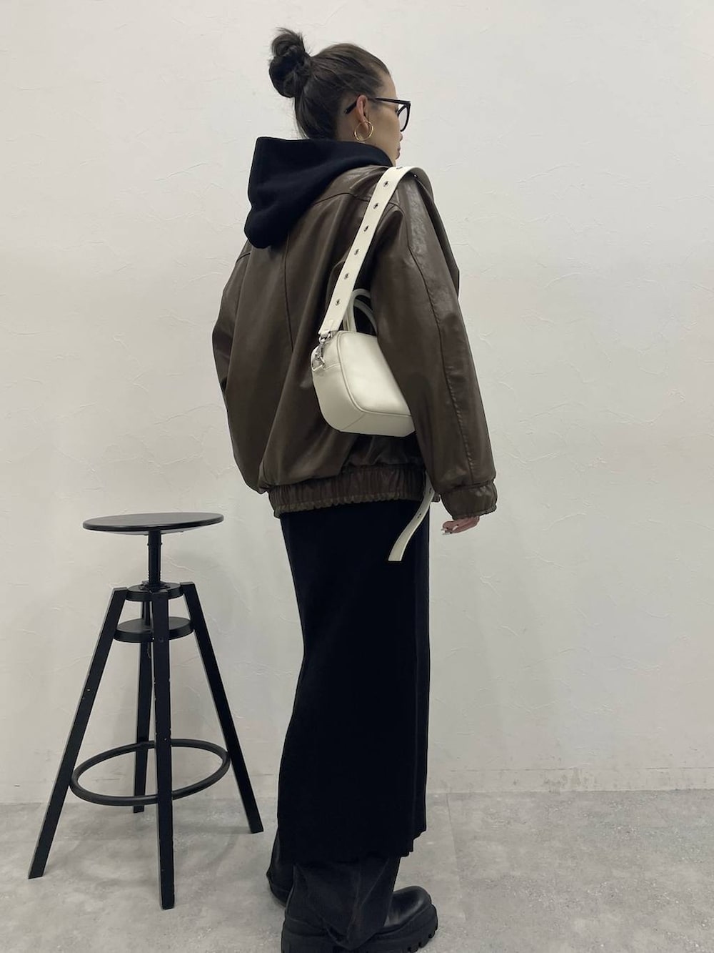 ホワイト系のショルダーバッグ、グレー系のデニムパンツ、ブラック系のブーツを着用したレディースの冬コーディネートの3枚目の写真