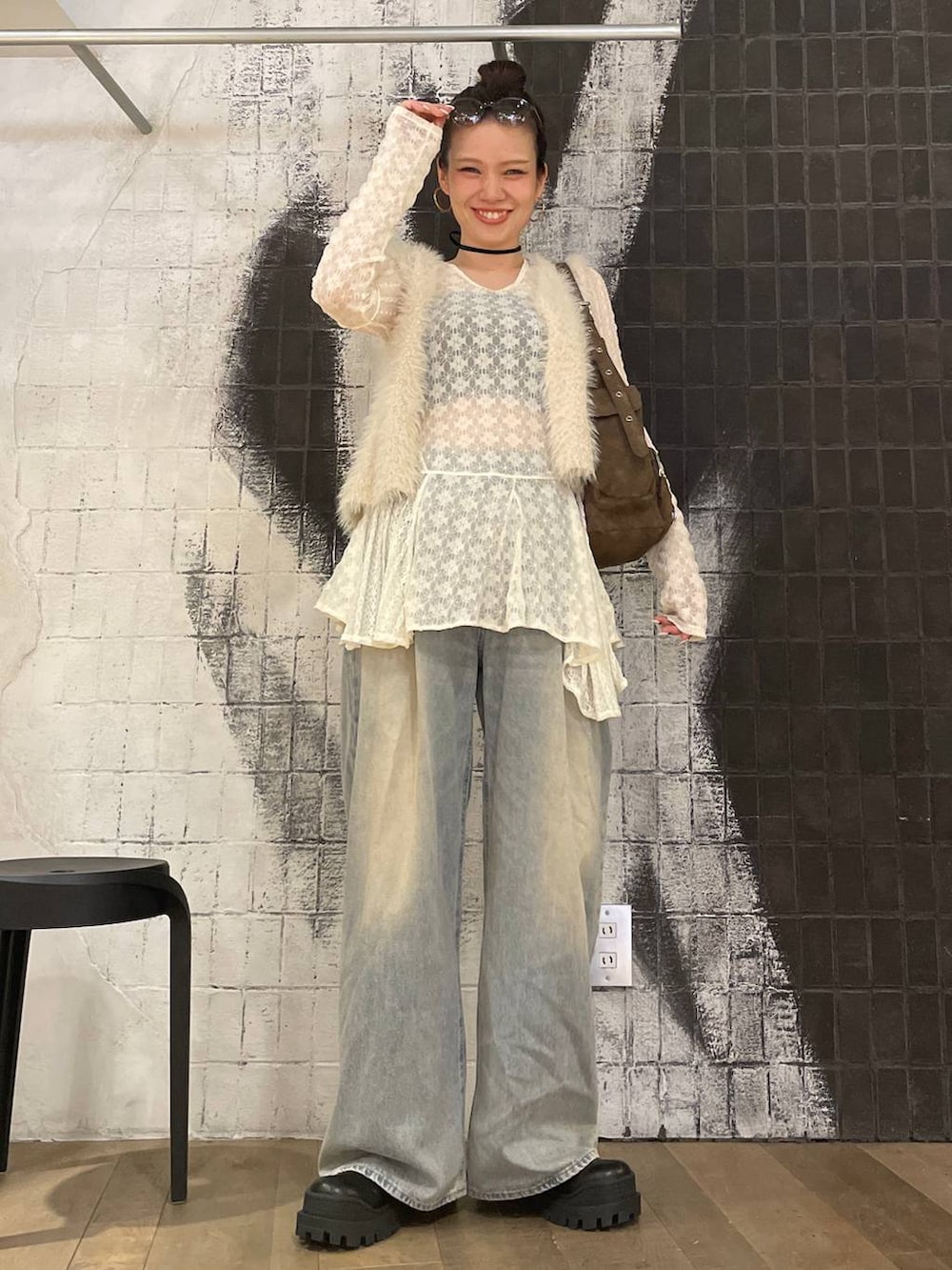 ホワイト系のベスト、ブルー系のデニムパンツ、ブラウン系のショルダーバッグを着用したレディースの秋コーディネートの2枚目の写真