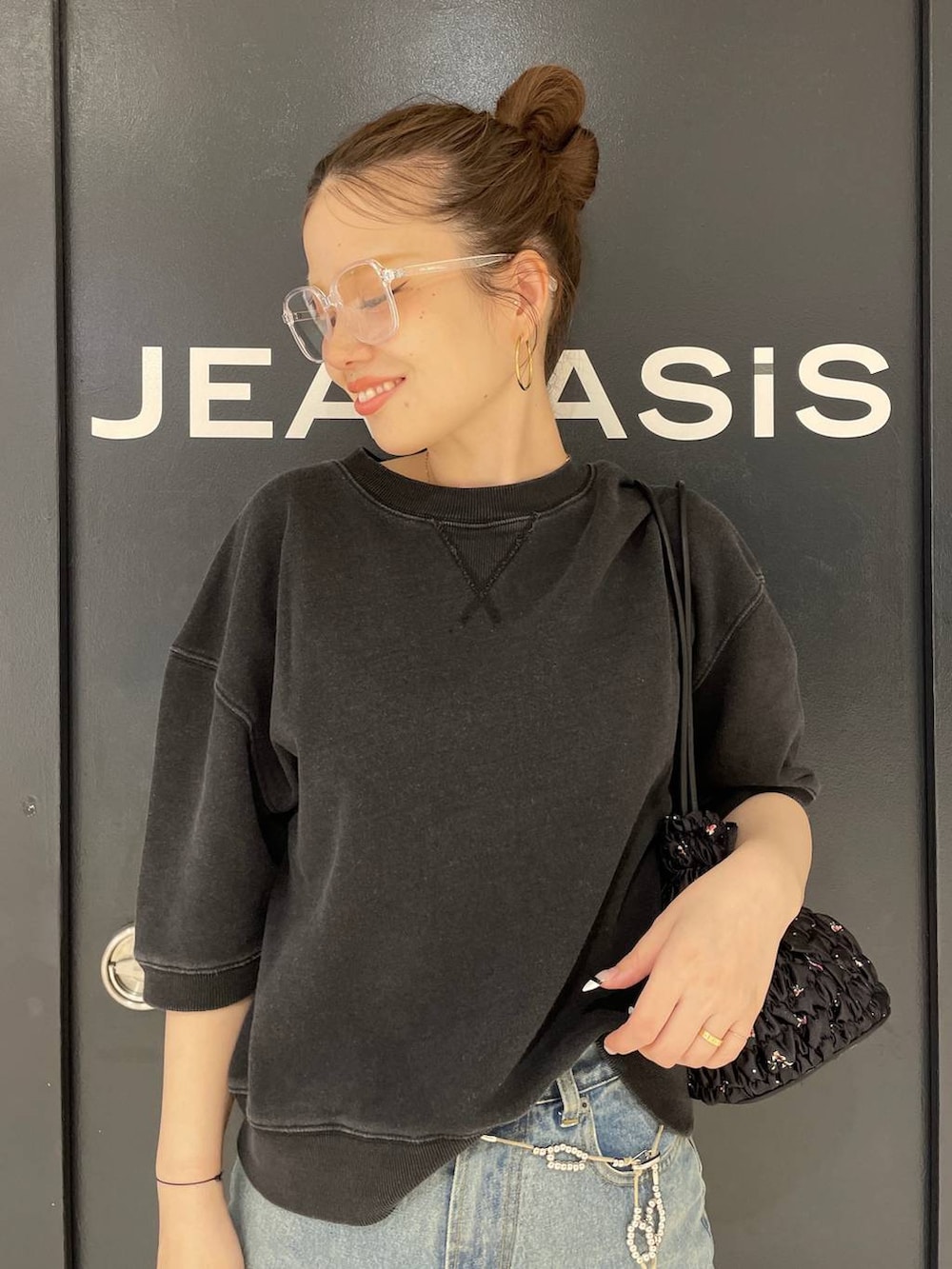 ブルー系のデニムパンツ、ブラック系のスウェット、ブラック系のショルダーバッグを着用したレディースの夏コーディネートの6枚目の写真