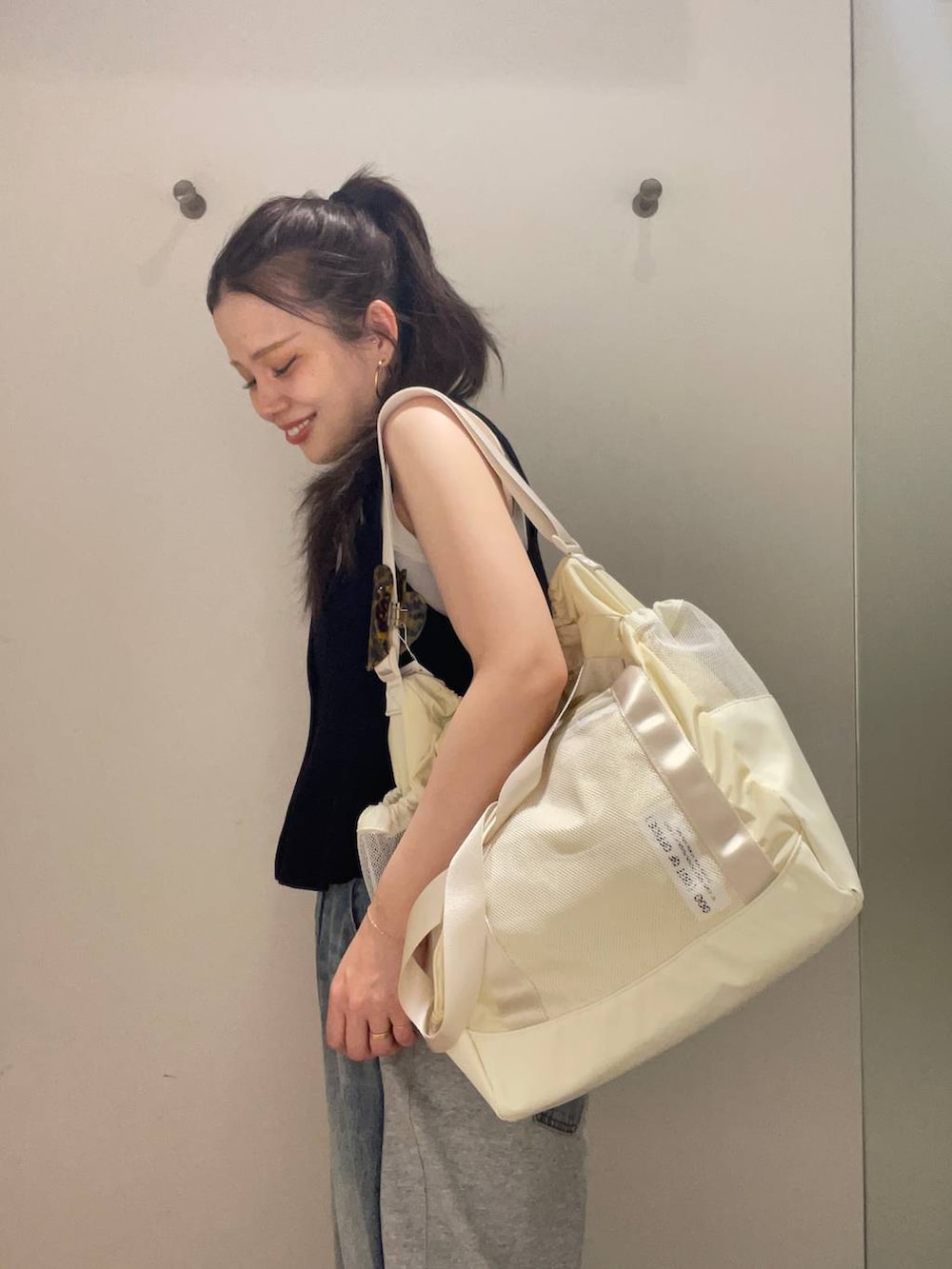 ブルー系のデニムパンツ、ホワイト系のタンクトップ、ベージュ系のサンダルを着用したレディースの春コーディネートの3枚目の写真