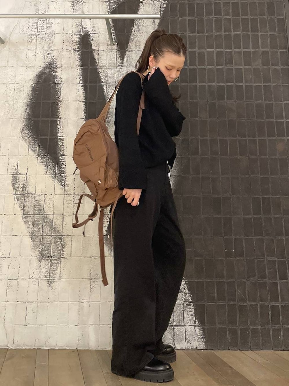 ブラック系のデニムパンツ、ブラック系のニット/セーター、ブラウン系のバックパック/リュックを着用したレディースの冬コーディネートの6枚目の写真