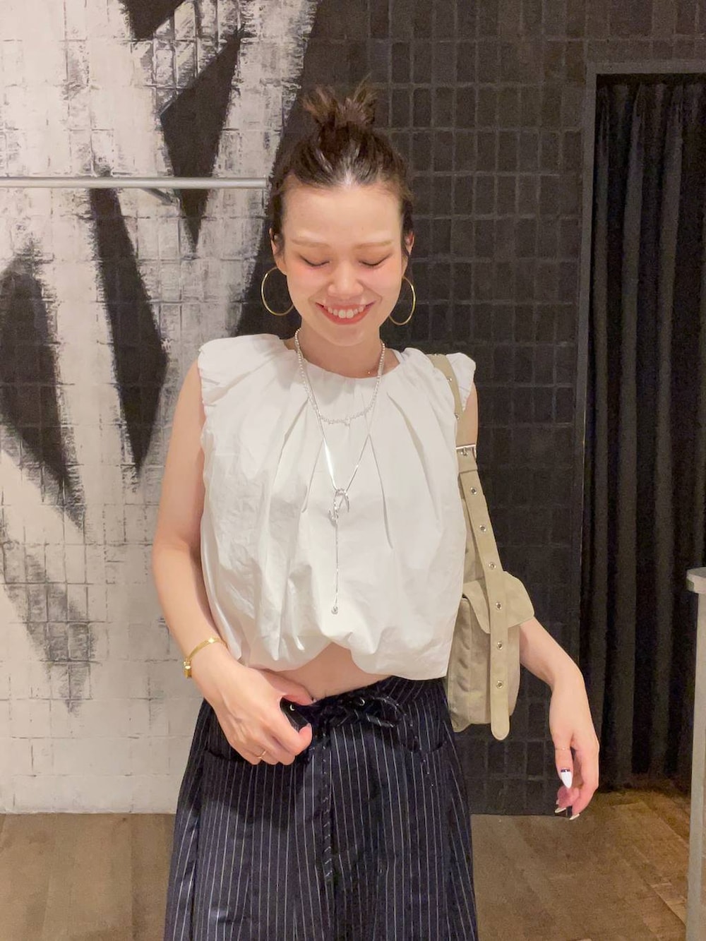 シルバー系のサンダル、ベージュ系のショルダーバッグ、ブルー系のスラックスを着用したレディースの夏コーディネートの2枚目の写真
