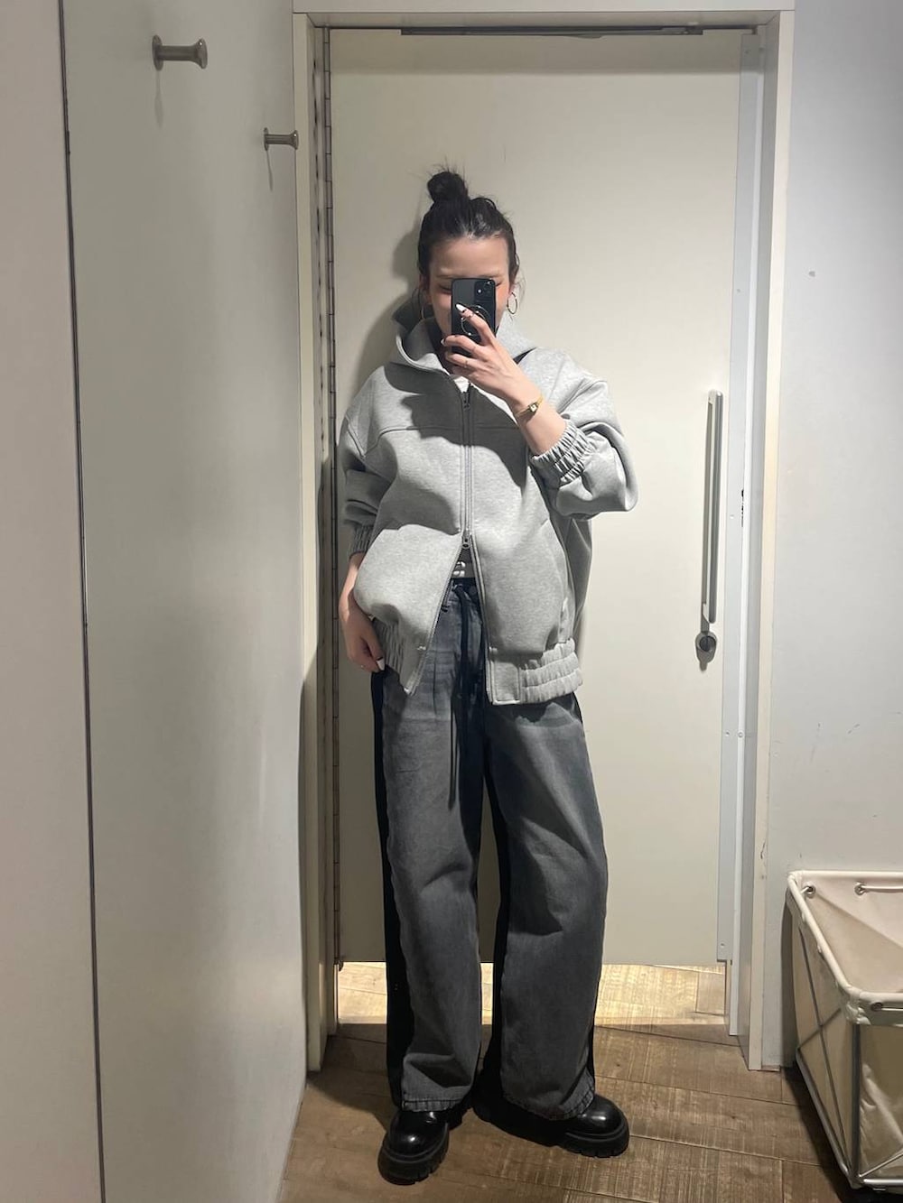 グレー系のパーカー、ブラック系のデニムパンツ、ゴールド系のピアス（両耳用）を着用したレディースの冬コーディネートの3枚目の写真