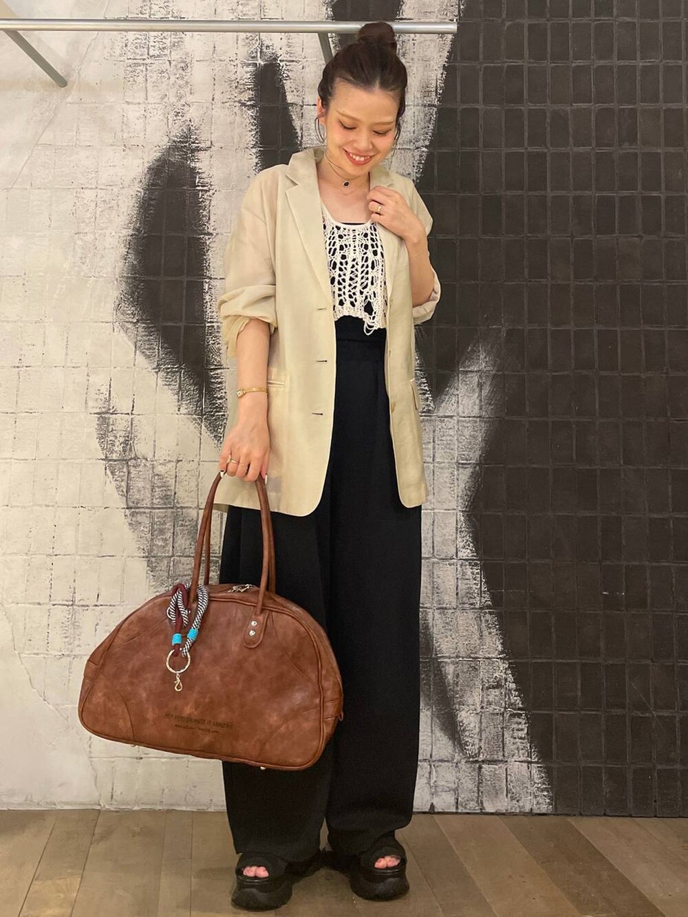 ホワイト系のベスト、ブラック系のサンダル、ブラウン系のボストンバッグを着用したレディースの夏コーディネートの6枚目の写真