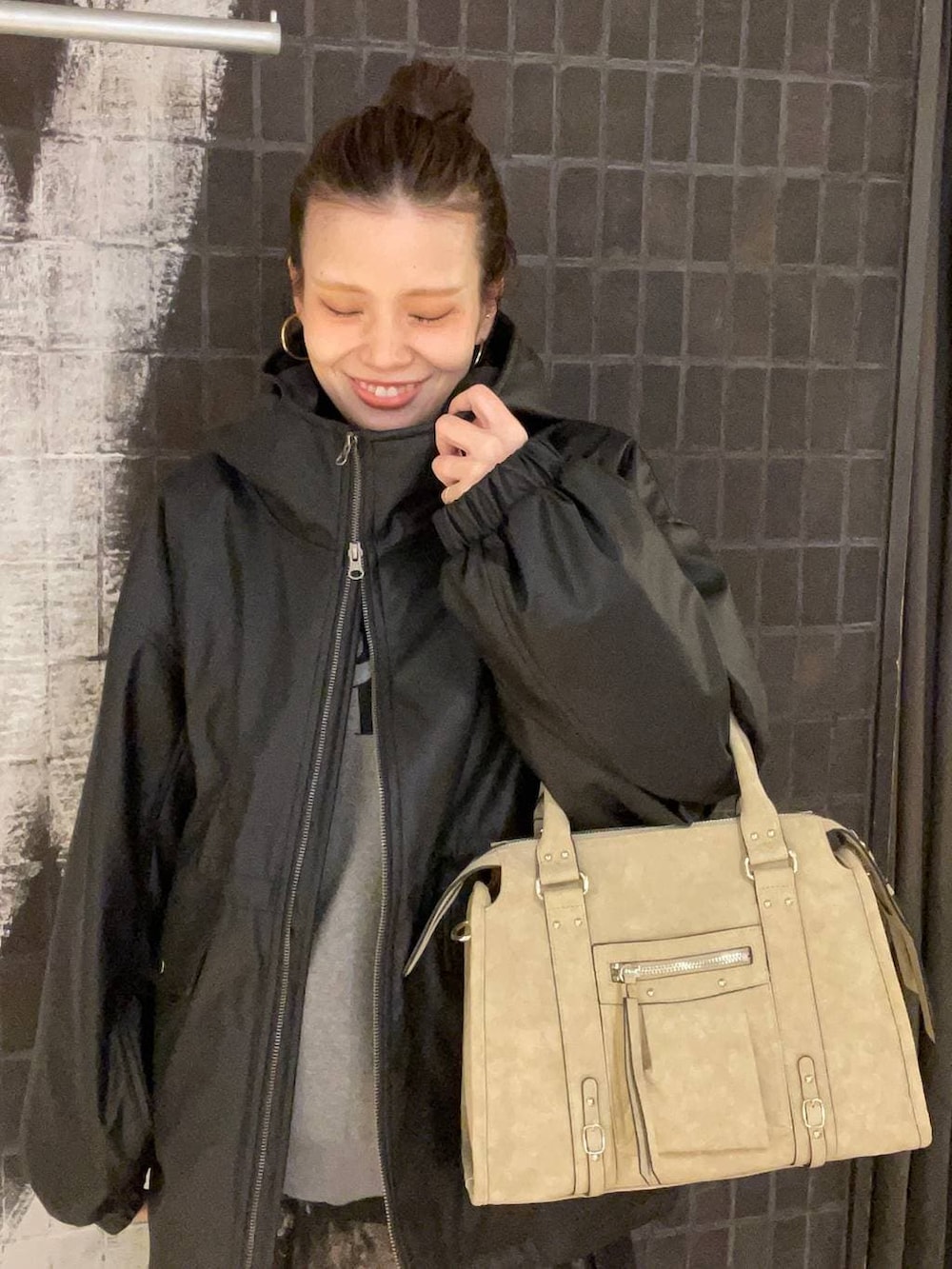 ベージュ系のボストンバッグ、ブラック系のブーツ、ブラック系のスカートを着用したレディースの冬コーディネートの5枚目の写真