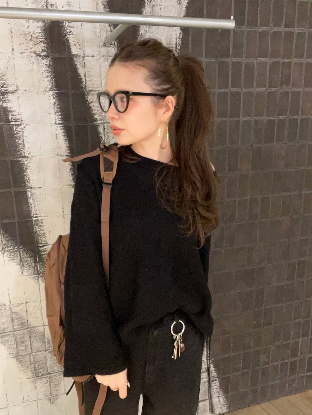 ブラック系のデニムパンツ、ブラック系のニット/セーター、ブラウン系のバックパック/リュックを着用したレディースの冬コーディネートの7枚目の写真