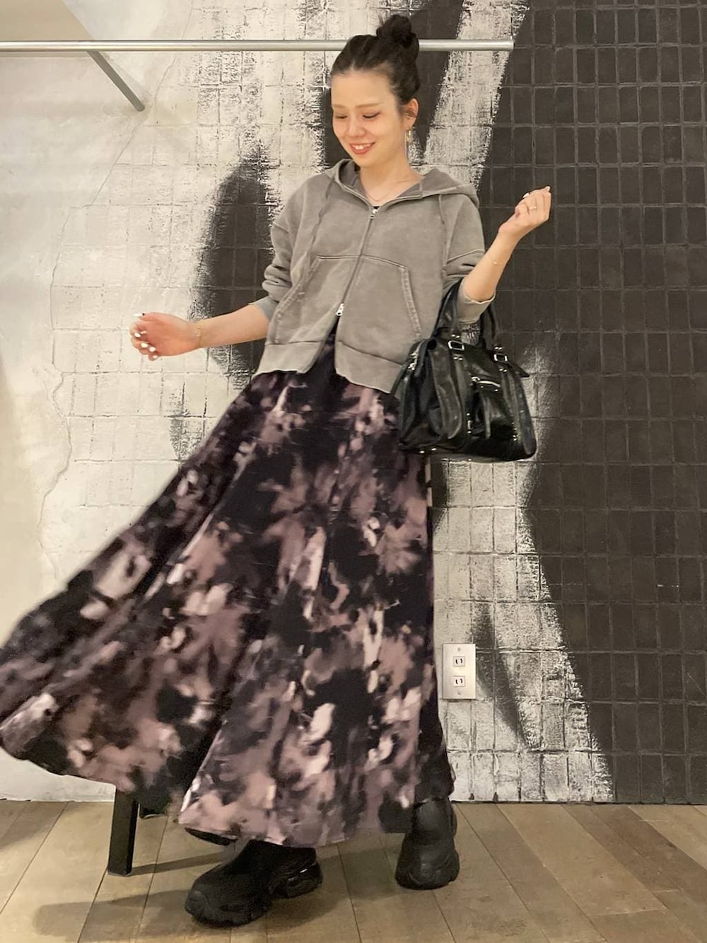 グレー系のパーカー、ブラック系のボストンバッグ、ブラック系のブーツを着用したレディースの秋コーディネートの3枚目の写真