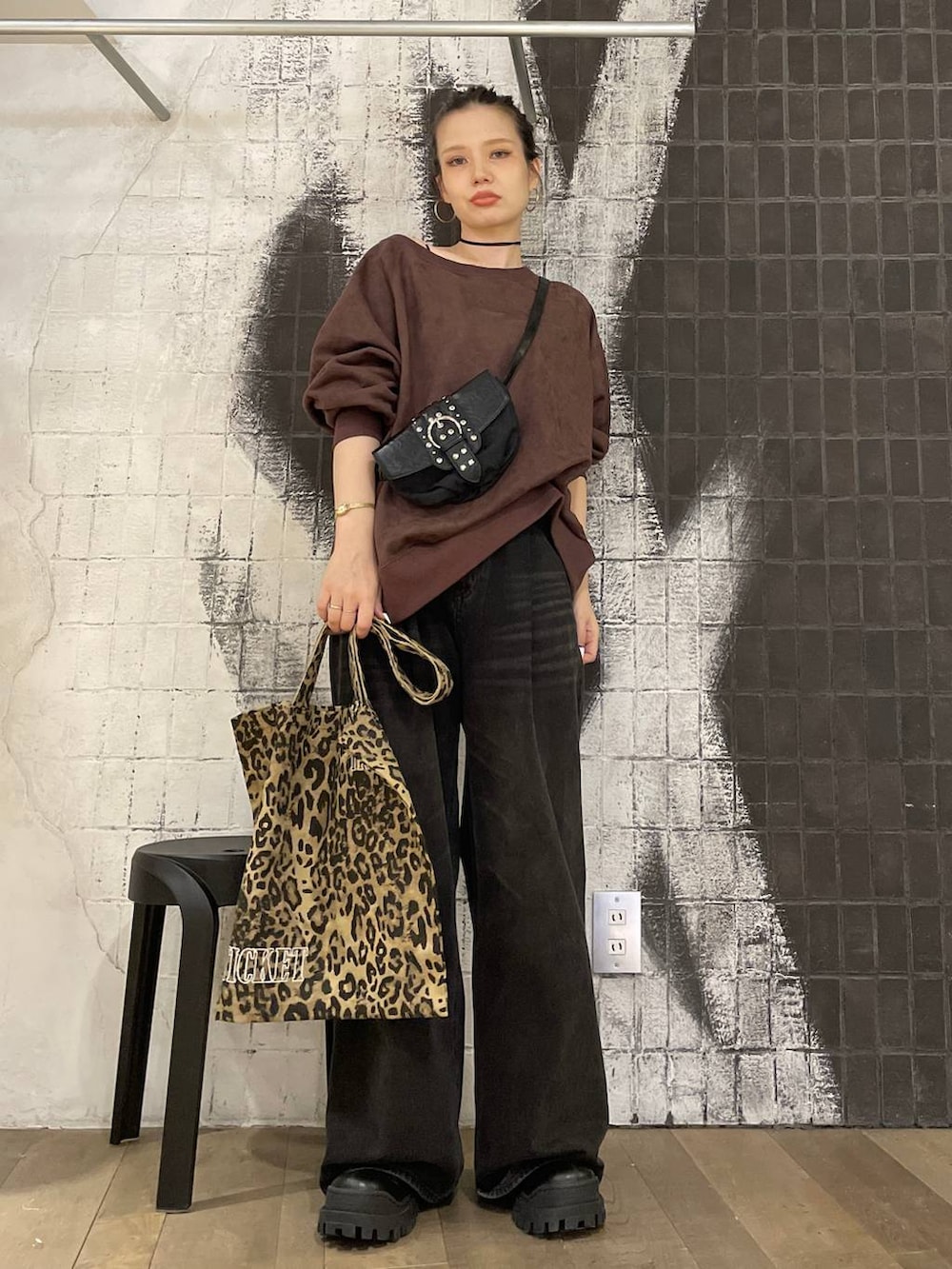 グレー系のデニムパンツ、ブラック系のショルダーバッグ、ブラック系のブーツを着用したレディースの秋コーディネートの2枚目の写真