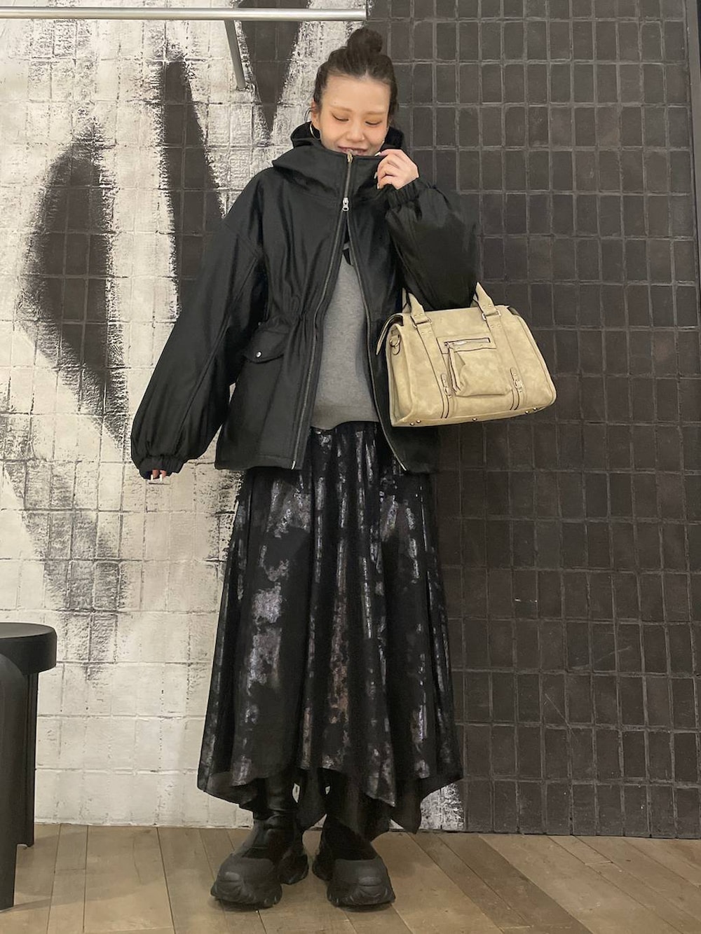 ベージュ系のボストンバッグ、ブラック系のブーツ、ブラック系のスカートを着用したレディースの冬コーディネートの2枚目の写真