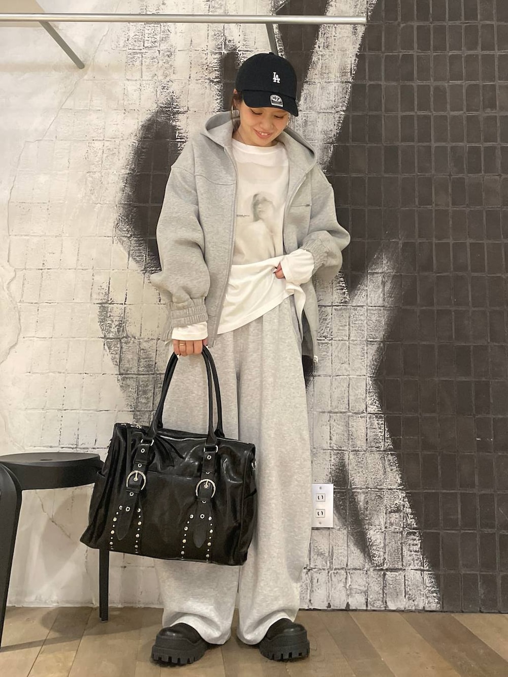 グレー系のパーカー、ブラック系のトートバッグ、ブラック系のブーツを着用したレディースの秋コーディネートの4枚目の写真
