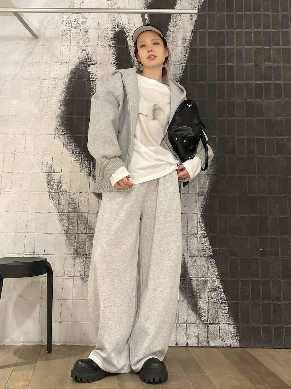 グレー系のパーカー、ブラック系のトートバッグ、ブラック系のブーツを着用したレディースの秋コーディネートの5枚目の写真