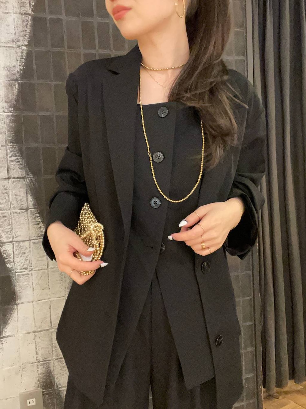 ブラック系のテーラードジャケット、ブラック系のローファー、ゴールド系のピアス（両耳用）を着用したレディースの冬コーディネートの5枚目の写真
