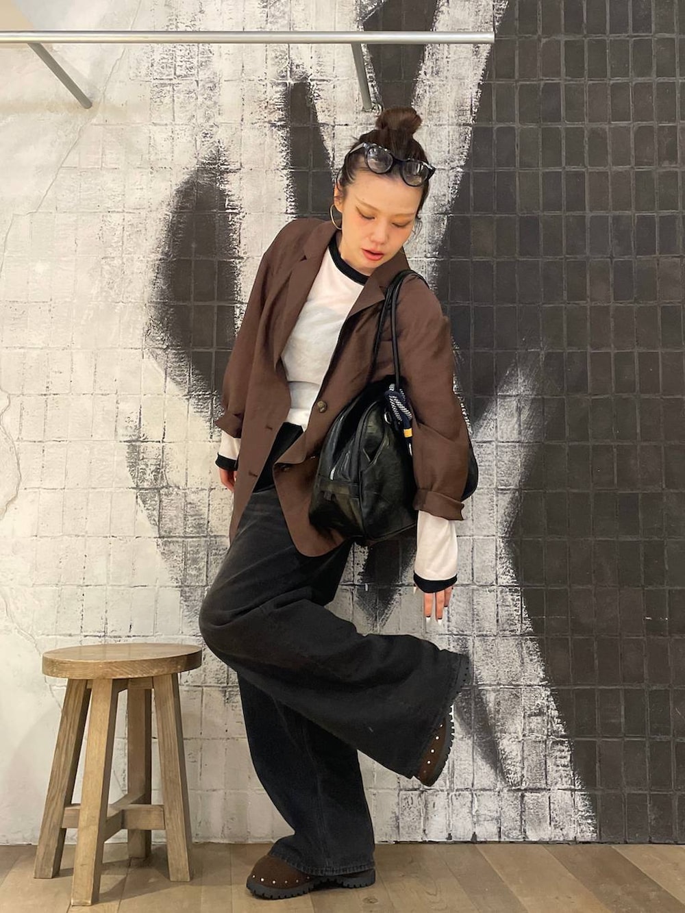 グレー系のデニムパンツ、ブラック系のボストンバッグ、ブラウン系のサンダルを着用したレディースの秋コーディネートの7枚目の写真